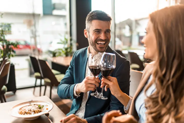 A smiling couple sharing eye contact and enjoying a relaxed conversation, symbolizing mutual attraction and connection.