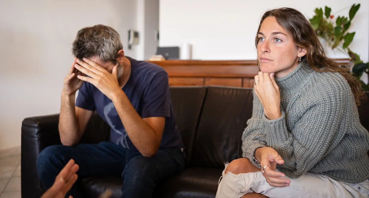 Emotionally disconnected couple sitting apart on a couch, representing the warning signs of a silent divorce.