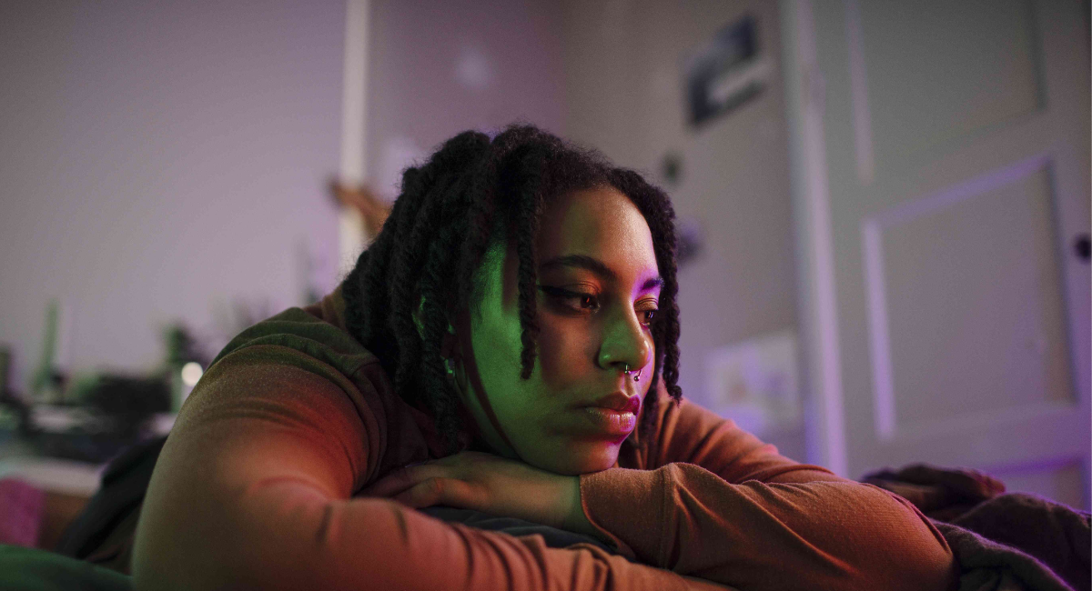 A person sitting thoughtfully with dark clouds above their head, symbolizing negative thoughts affecting emotions, confidence, and daily life.