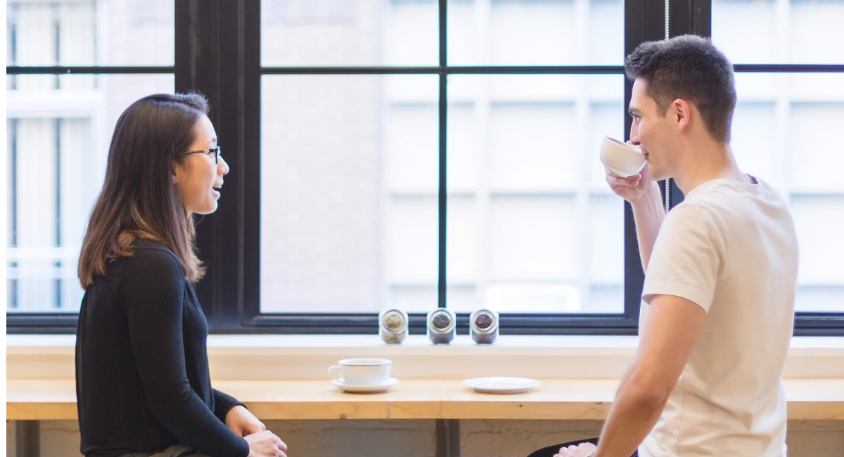 A couple sitting together and having an open conversation while practicing healthy communication skills to strengthen their relationship.